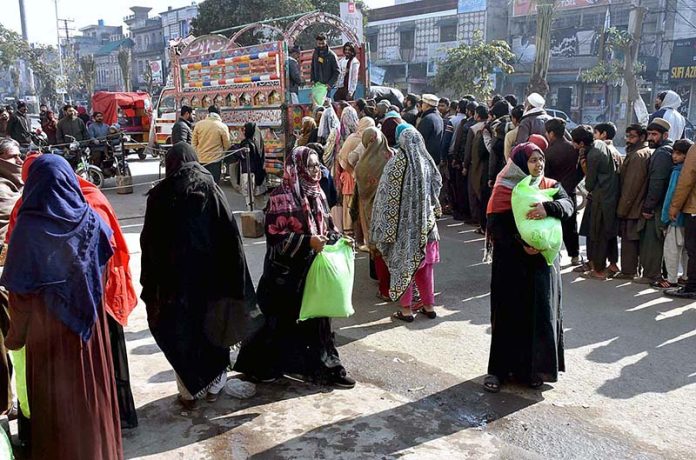 A large number of People standing in a long queue and waiting for their turn to purchase wheat flour at subsidized price by government at Shahabpura in the city