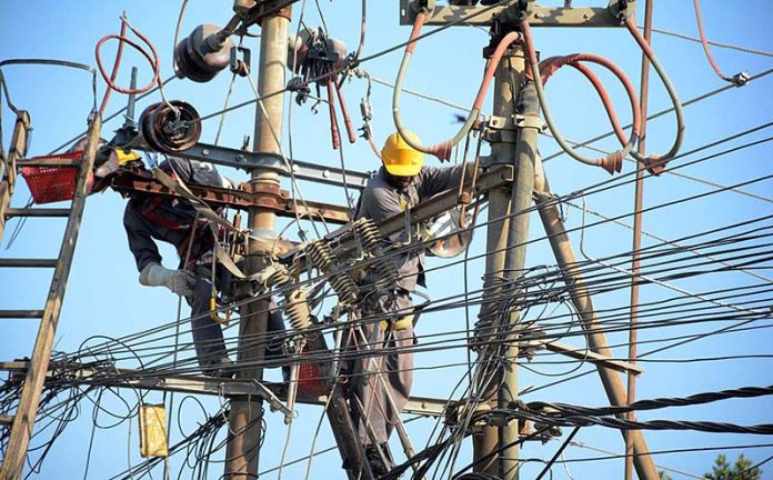 K Electric workers removing faults from electricity lines on an electric pole