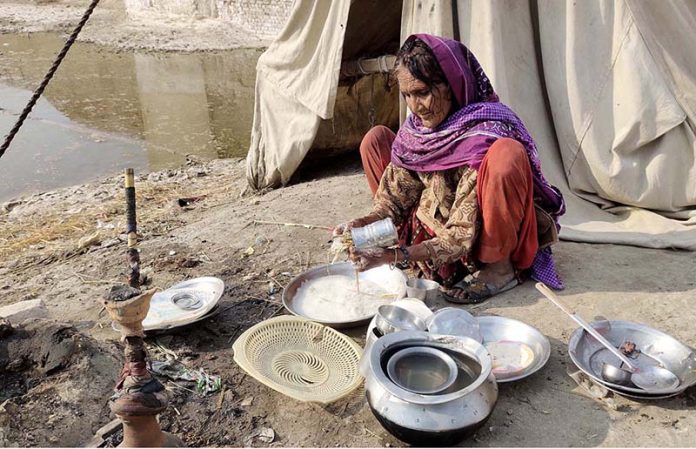 A nomad woman washing pots in outside her Makeshift Shelter
