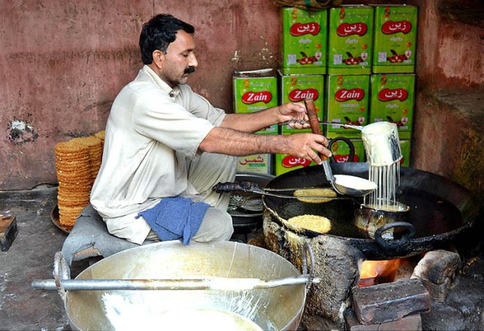 A shopkeeper prepares traditional sweet item at Gawal Mandi Road