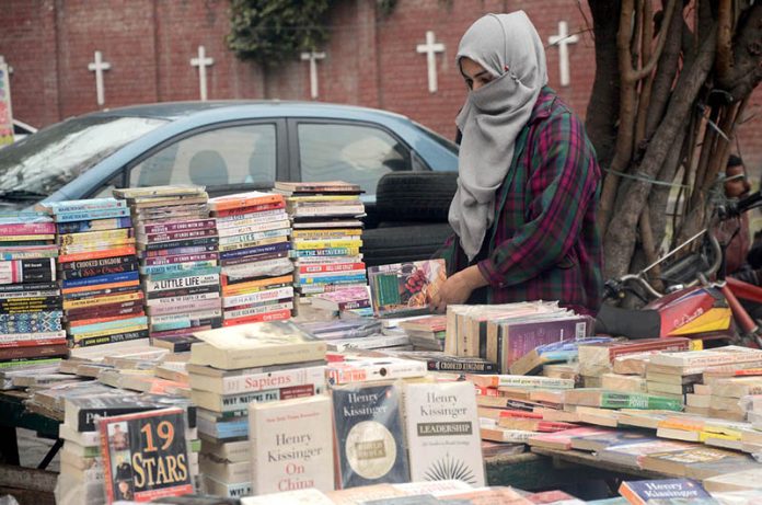 A Girl selecting the books displayed by a vendor at Provincial Capital.