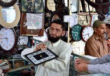 A vendor selling wall clocks on his shop near Taxali Gate