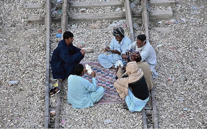 People playing cards in their leisure time at railway tracks