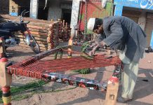 A labourers is knitting the traditional bed (Charpai) for customers at his workplace