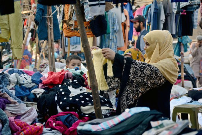 A woman purchasing used children clothes at a roadside stall in Saddar