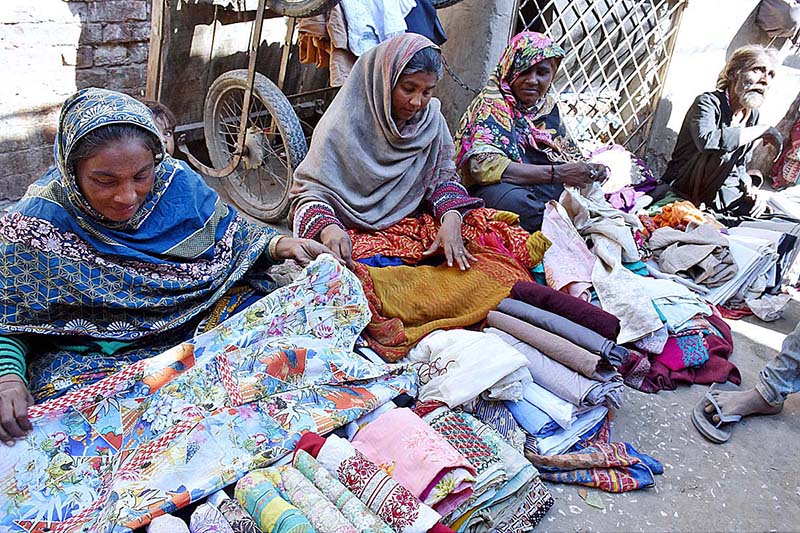 Lady vendors arranging and displaying used clothes to attract customers at his roadside setup