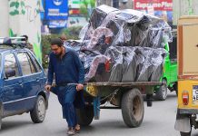 A labourer on the way pulling a handcart loaded with sofas on Murree Road