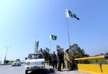 CDA workers fixing national flags on flyover at Srinagar Highway in connection with National Day of Pakistan