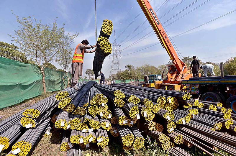 Labourers busy in unloading iron rods on worksite during construction work at Murree Road