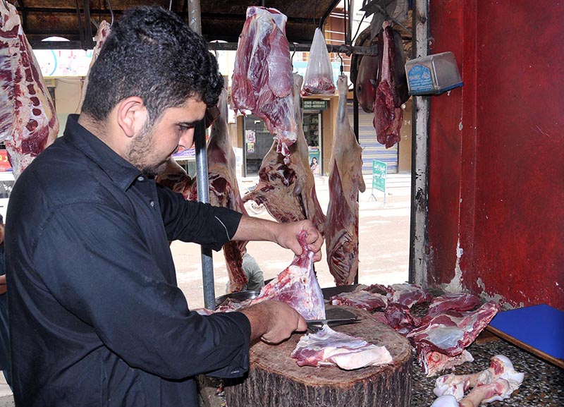 A butcher cutting meat for selling at his shop during a holy fasting month of Ramazan ul Mubarak in the Federal Capital