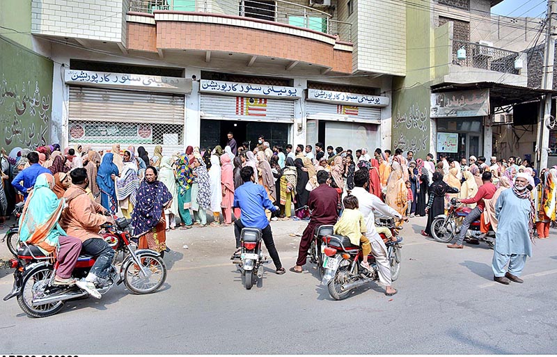 A large number of people standing in queue outside Utility Store to get free flour bags under “Ramadan Package” at Millat Road