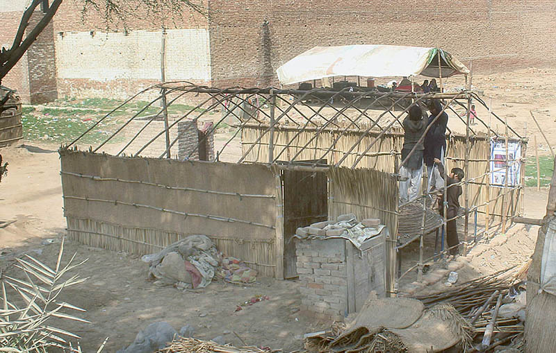 A gypsy family busy in assembling a makeshift home on a roadside