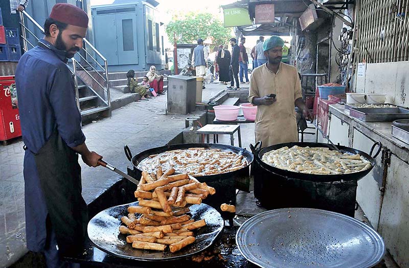 Vendors frying traditional food item for iftar at Karachi Company during Holy month of Ramzan in Federal Capital.