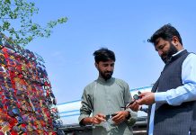 Vender selling and displaying glasses to the customers at his roadside setup