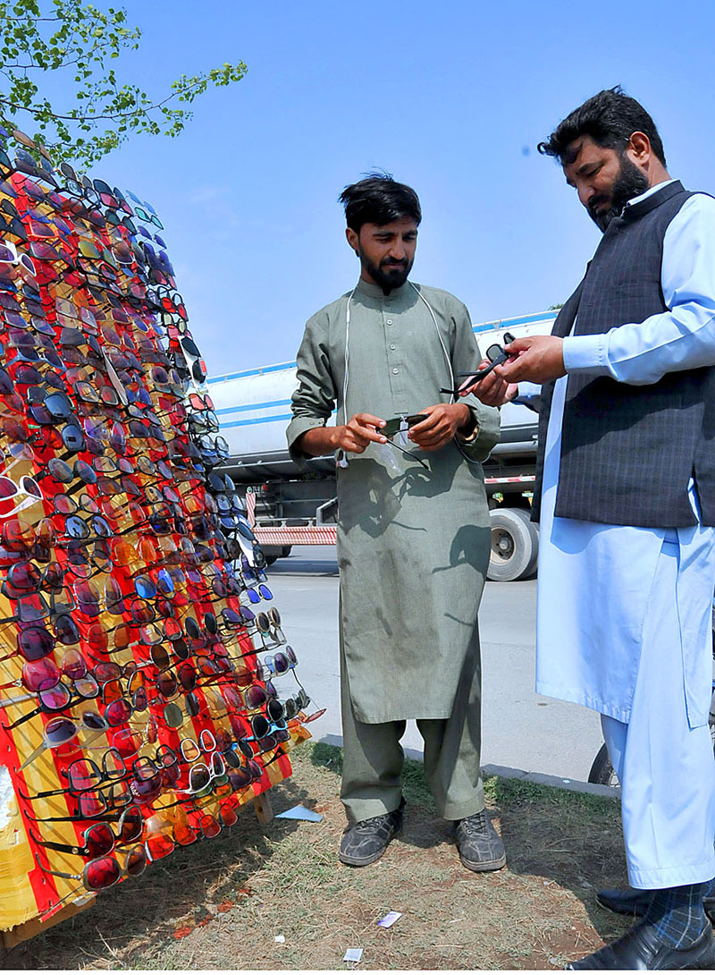 Vender selling and displaying glasses to the customers at his roadside setup