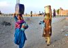 Gypsy women carrying pots on their head back after filling clean water at Qasimabad
