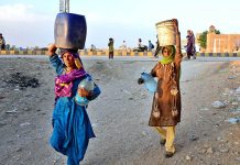 Gypsy women carrying pots on their head back after filling clean water at Qasimabad