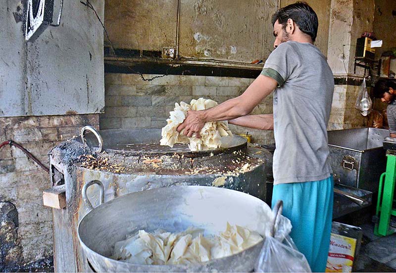A cook is frying snacks for a desh Dahi Bhale at his shop
