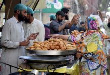 Woman purchasing traditional food item for iftari during the holy fasting month of Ramzan Ul Mubarak at Lakshmi Chowk
