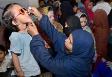 A health worker administering polio vaccine to a child during Polio Free Pakistan Campaign at Latifabad