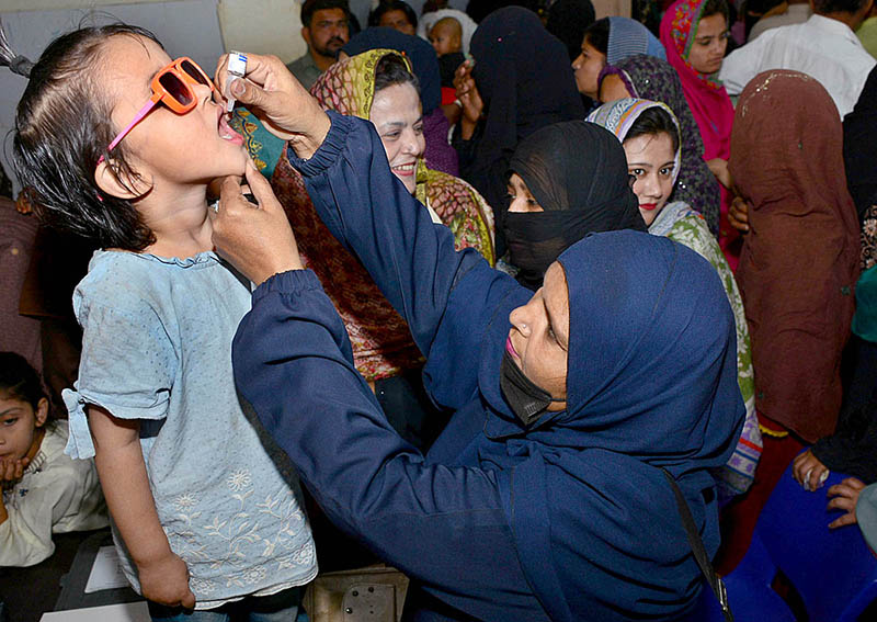 A health worker administering polio vaccine to a child during Polio Free Pakistan Campaign at Latifabad