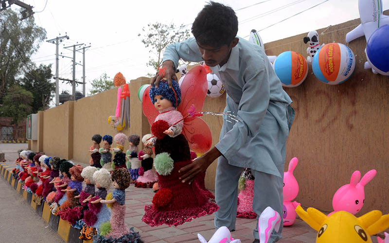 A vendor displaying plastic dolls to attract the customer at roadside setup