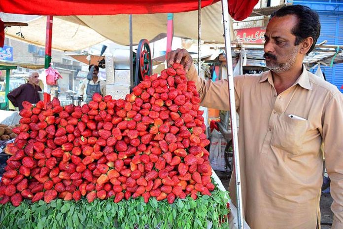 A vendor arranging and displaying strawberry to attract the customers on his cart