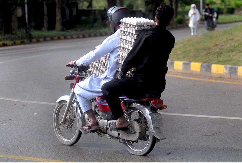 A family on his way to cover with sheet to protect from rain on motorbike at Federal Capital