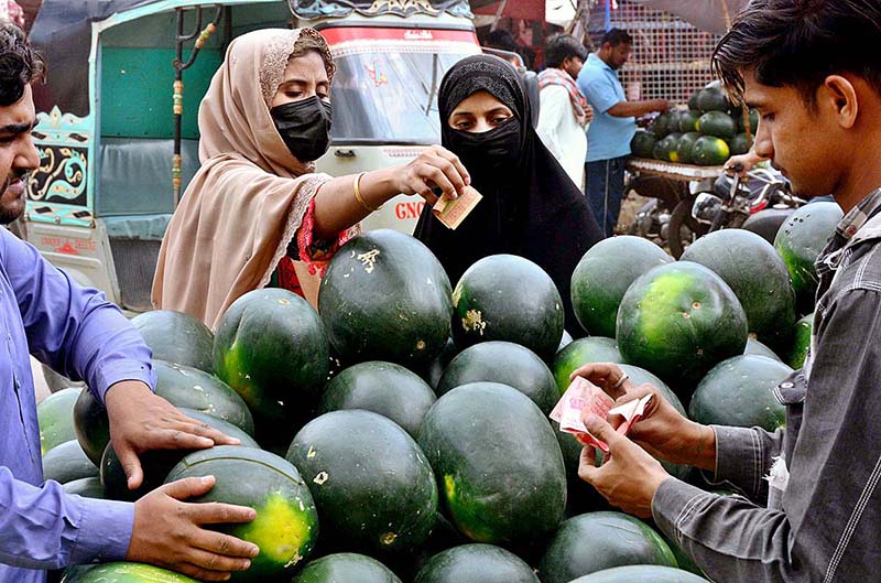Women purchasing watermelon from vendor on the first day of Holy Fasting Month of Ramzan at Latifabad