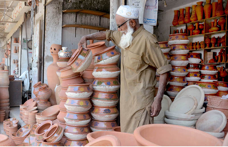 Shopkeeper displaying and arranging clay-made Cooking pots to attract the customers on his shop