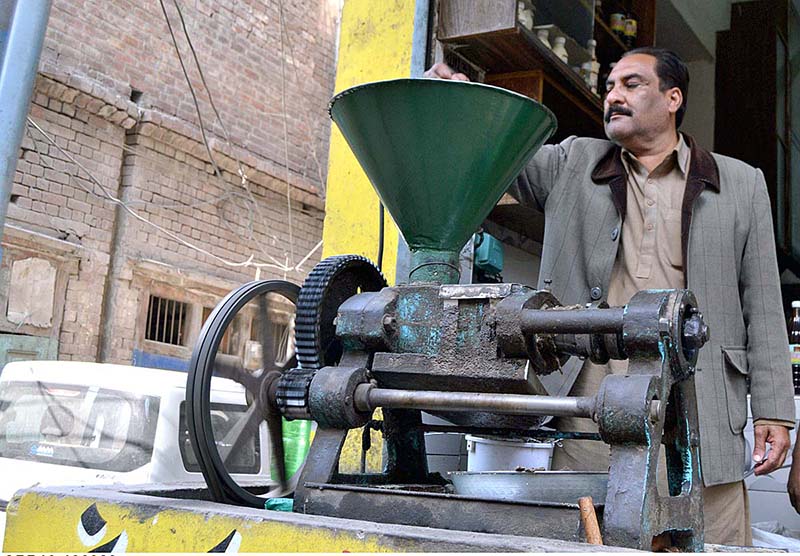 A shopkeeper extracting mustard oil with machine in a traditional way