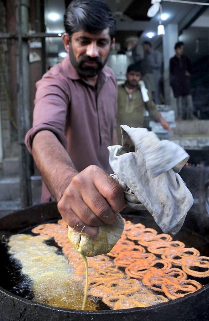 A vendor busy in preparing traditional food item (jalebi) to attract the customers during Holy fasting month of Ramazan