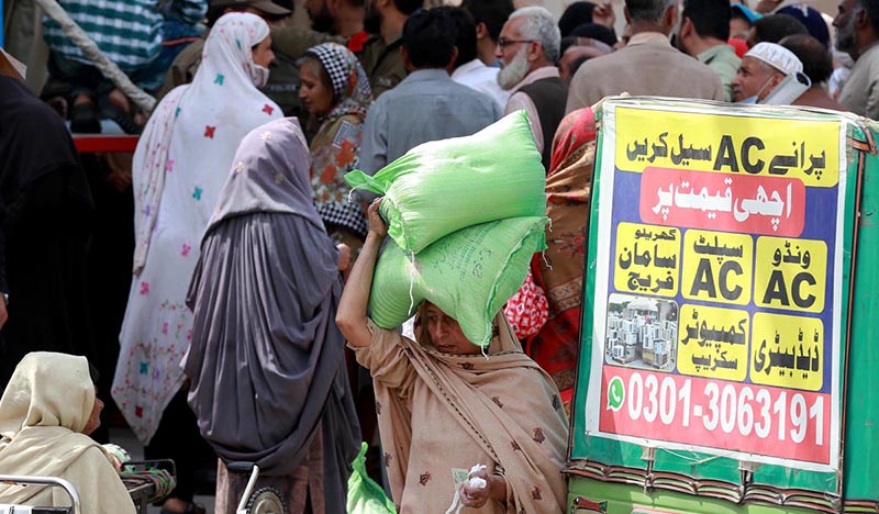 People standing in a queue to receive free flour bags from a distribution point under Prime Minister’s Ramazan package for deserving families at Chaklala Road