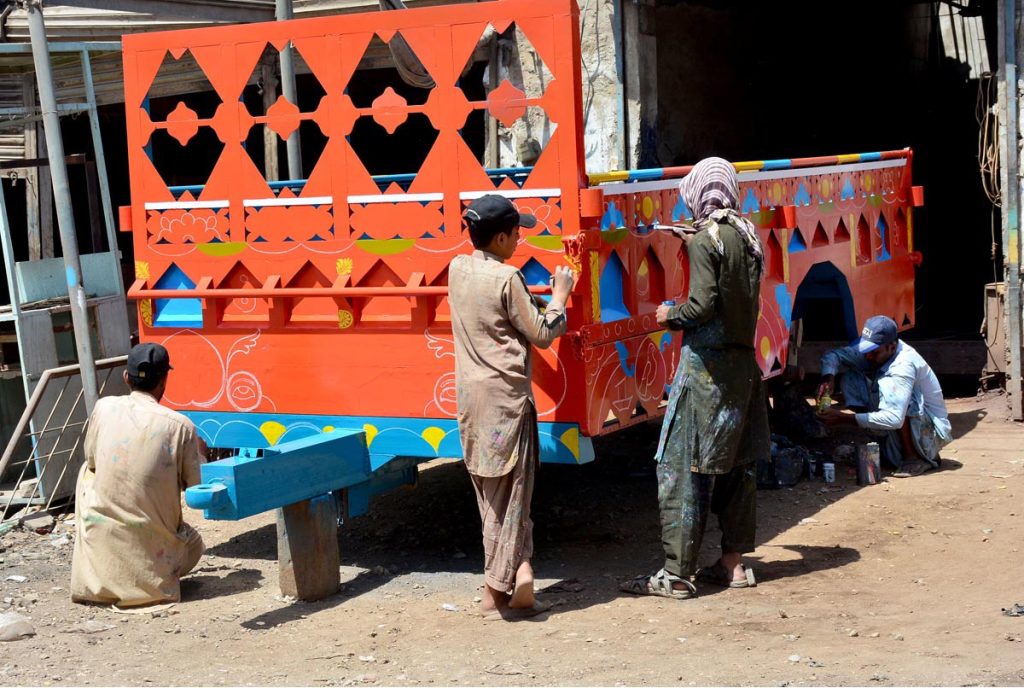 Painters busy in paint on the tractor trolley at his workplace