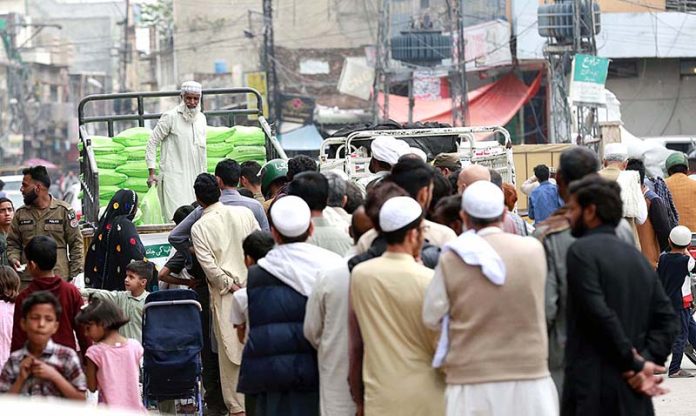 People standing in queue for getting free flour bags under Ramzan Package at Dhoke Khabba.