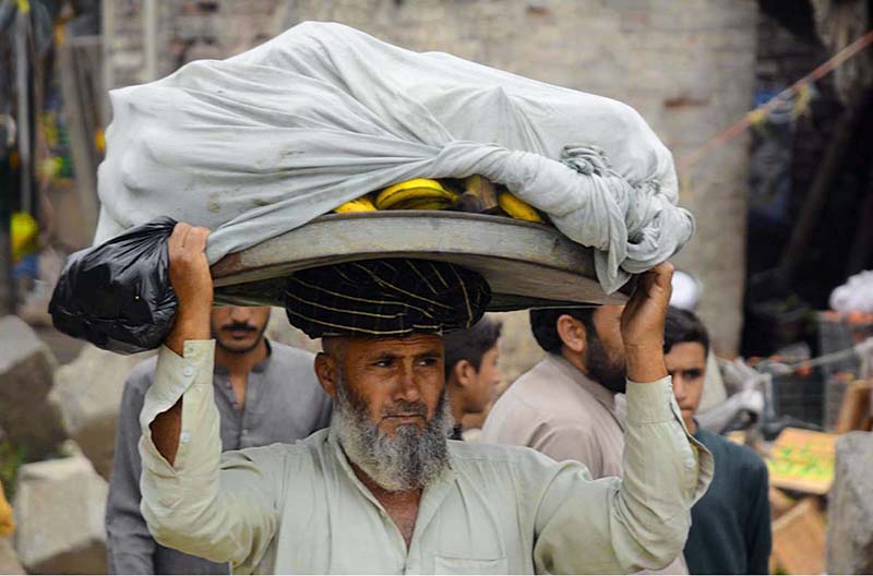 An old hawker carrying bananas on his head for selling in the local market