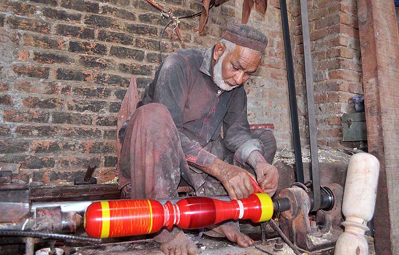 A worker color the part of a traditional bed (charpai) on his work place