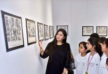 Teacher briefs the students about photos displayed during an exhibition in connection with Pakistan Day
