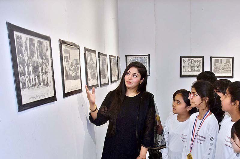Teacher briefs the students about photos displayed during an exhibition in connection with Pakistan Day