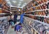 Shopkeeper arranging and displaying traditional shoes “Peshawari Chappal” at their shop to attract the customers at Bacha Khan Chowk.
