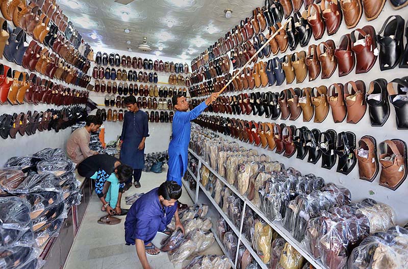 Shopkeeper arranging and displaying traditional shoes “Peshawari Chappal” at their shop to attract the customers at Bacha Khan Chowk.