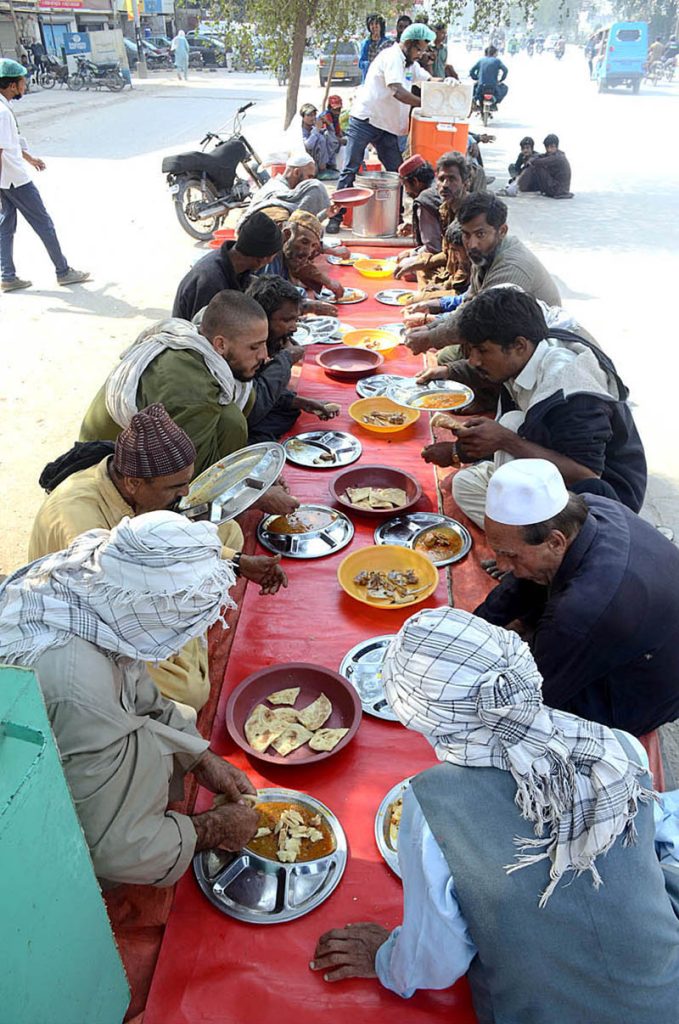 Deserving people eating lunch on a road side at Saylani Welfare Trust
