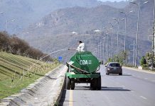 CDA worker busy in watering plants while sitting on the water tanker on green belts of 7th Avenue