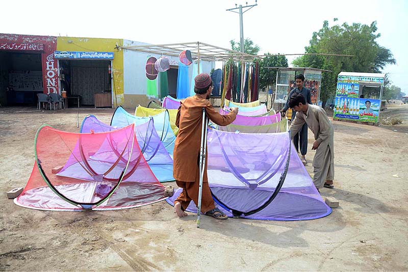 A Disabled vendor displaying mosquito nets to attract customers for selling to protect from mosquitoes and dengue fever at his roadside setup