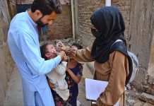 A health worker administering polio vaccine to a child during Polio Free Pakistan Campaign at Latifabad