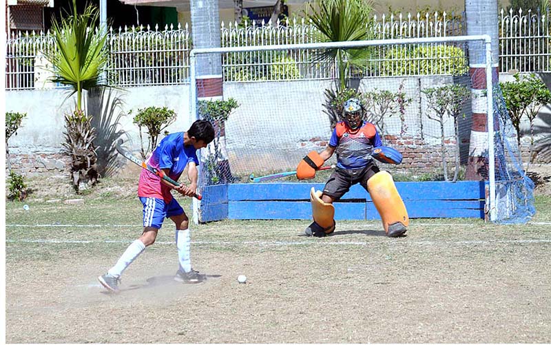 Hockey player in full action to hit the ball for score and goal keeper ready to controal the ball during the inter-collegiate hockey tournament organized by the Sargodha Education Board