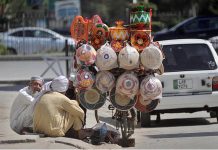 A hawker is selling beautiful and colorful handicrafts on his cycle on a roadside in Federal Capital