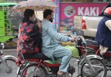 A woman holding an umbrella to protect from rain while riding on motorcycle in the Provincial Capital