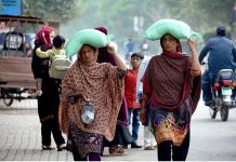 Women are returning back after getting free flour bags from a distribution center under Prime Minister’s Ramzan Relief Package for deserving families