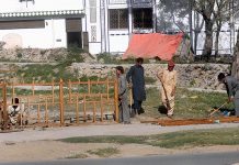 Laborers are installing iron fence on the edge of a CDA park on Khushal Khatak Road in a Federal Capital